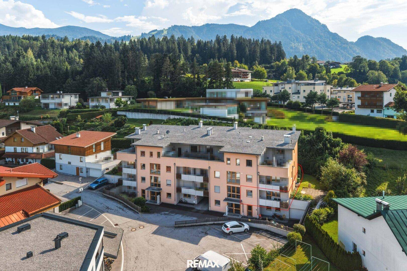 Luftaufnahme des Wohngebäudes in einer grünen Umgebung mit Bergblick.