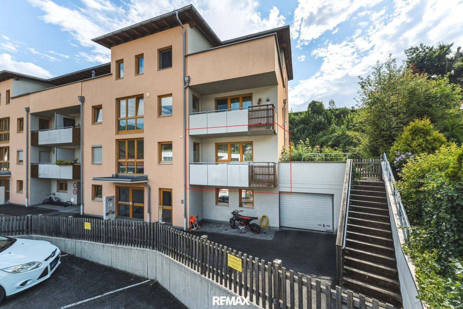Ansicht der Gebäudefassade mit Balkonen, Garagenzugang und Außentreppe.