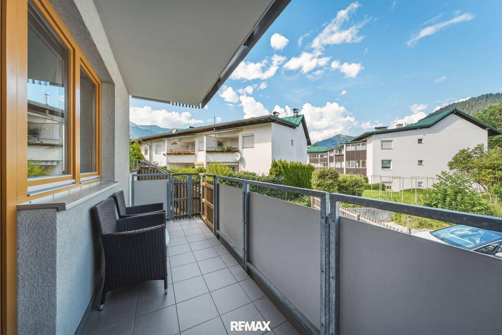 Kleiner Balkon mit Sitzgelegenheiten und Blick auf die umliegenden Häuser und Berge.
