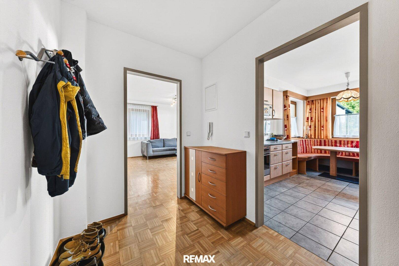 Heller Flur mit Parkettboden und offenen Zugängen zu Wohnzimmer und Küche.