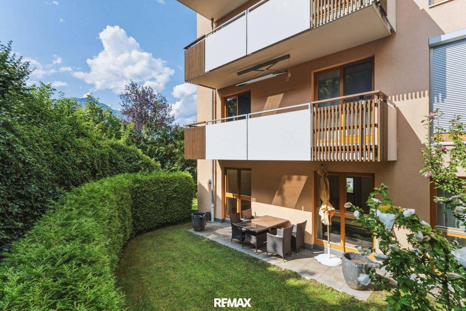 Großzügige Terrasse mit Gartenmöbeln und weitläufigem Rasenbereich vor dem Gebäude.