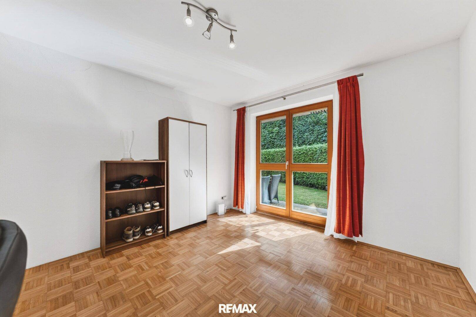 Geräumiges Zimmer mit Parkettboden und Zugang zum Gartenbereich.