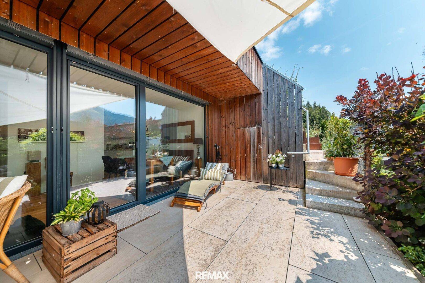 Attraktive Terrasse mit Steinplatten, Holzverkleidung und Liegestuhl, um die Sonne zu genießen.
