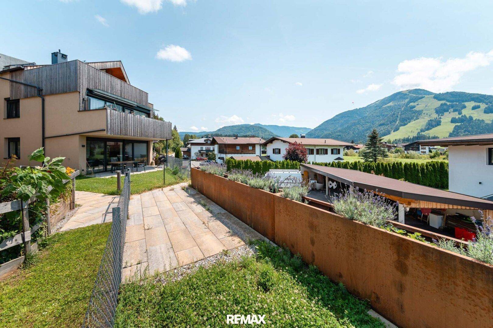 Weitläufiger Außenbereich mit Rasenfläche, Terrasse und Panoramablick auf die Berge.