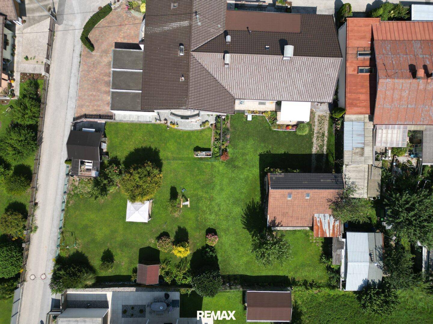 Vogelperspektive des Grundstücks mit großem Rasen, Gartenhaus und angrenzenden Gebäuden, rot umrandet.