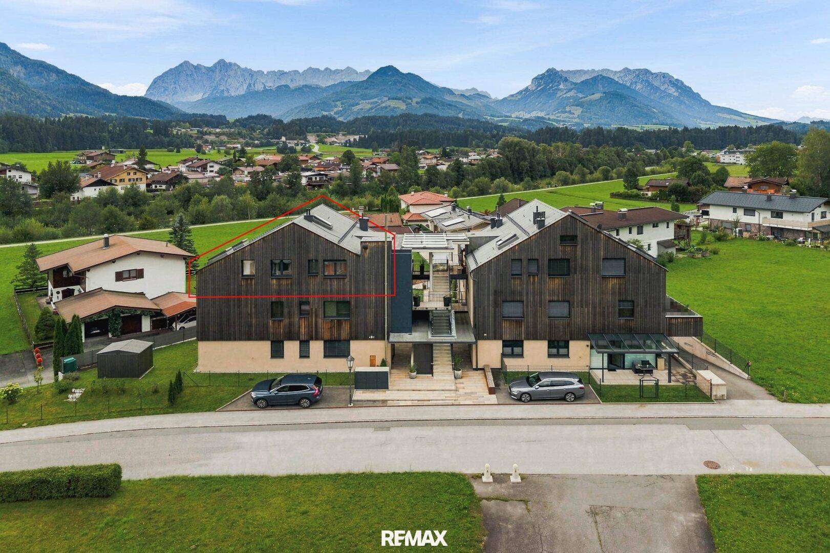 Vorderansicht eines modernen Wohngebäudes mit Holzfassade und Parkplätzen.