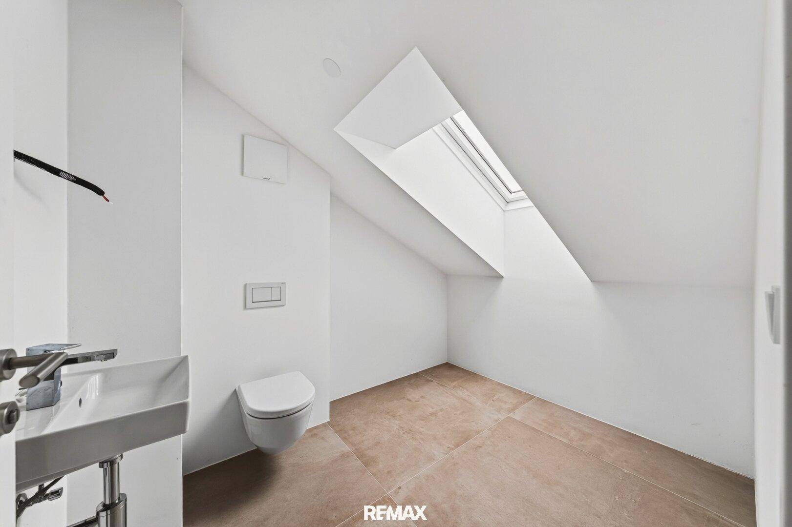 Gäste-WC mit Dachschräge, wandhängendem WC und Oberlicht für natürliches Licht.