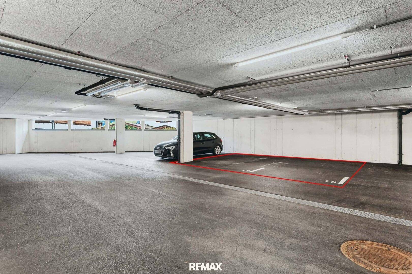 Tiefgaragenstellplatz mit Betonboden und Beleuchtung, markiert für ein Fahrzeug.