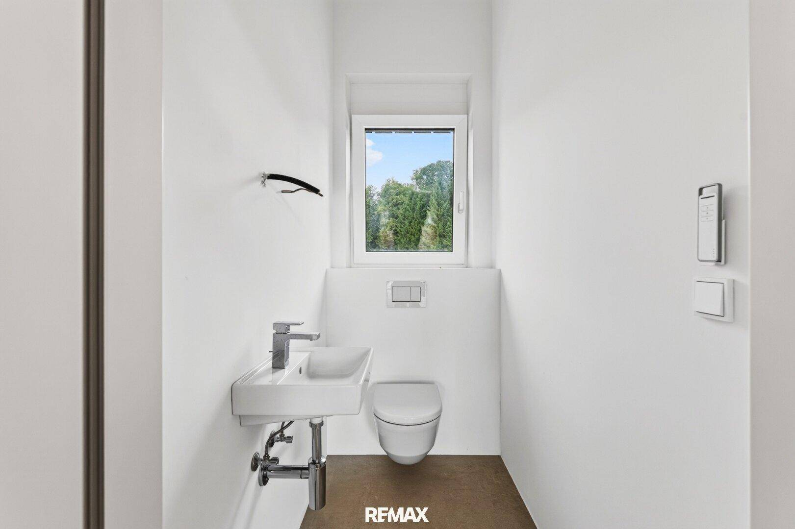 Kleines Gäste-WC mit wandhängendem WC, modernem Waschbecken und Fenster.