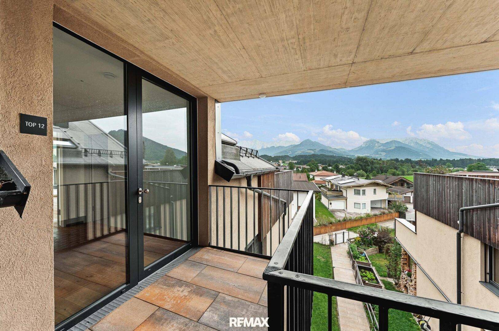 Überdachter Balkon mit Bergblick und moderner Metallbrüstung, ideal für entspannte Stunden.