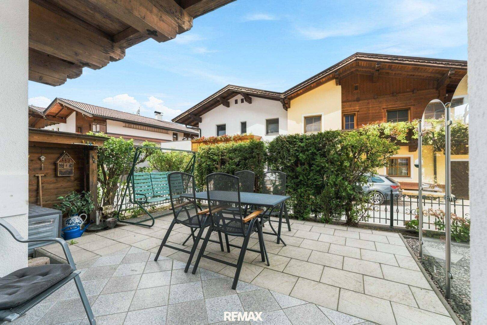 Gepflasterte Terrasse mit Gartenmöbeln und Hecke, ideal für entspannte Stunden im Freien.