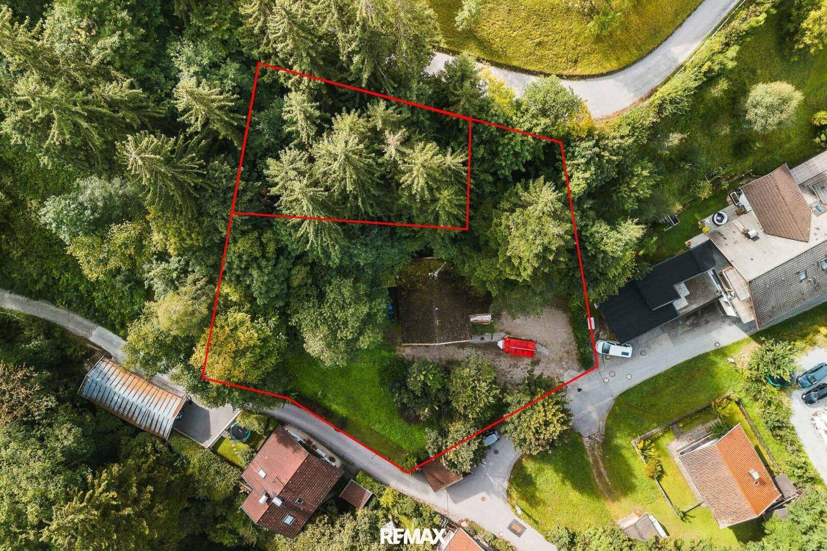 Luftaufnahme eines von Wald umgebenen Grundstücks mit roter Umrandung, die die Grenzen des Anwesens deutlich zeigt.