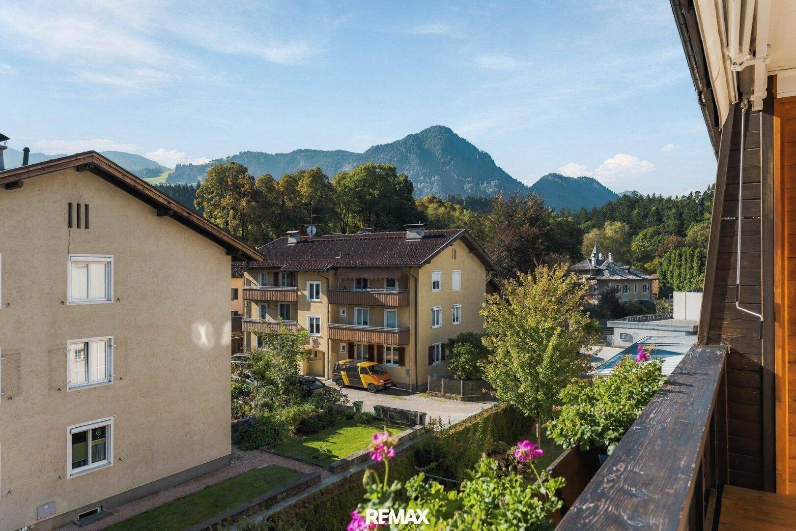 Panoramablick vom Balkon auf die umliegende Berglandschaft und Nachbargebäude.