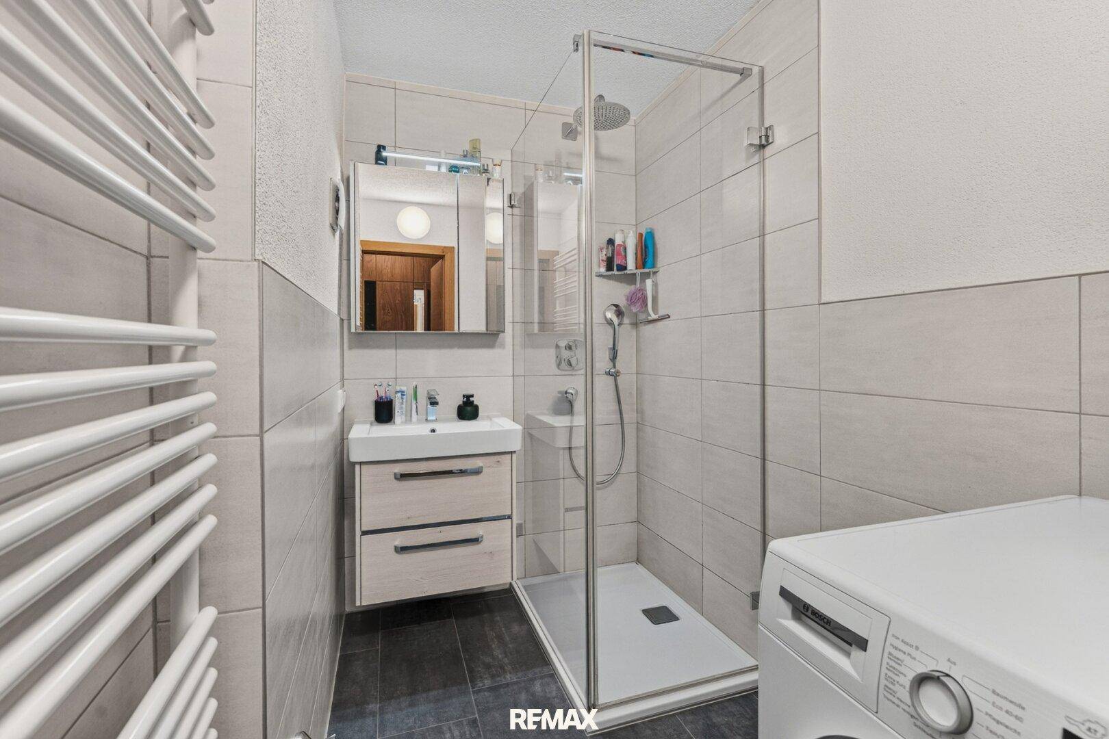 Modernes Badezimmer mit Dusche, Waschbecken und beheiztem Handtuchhalter.