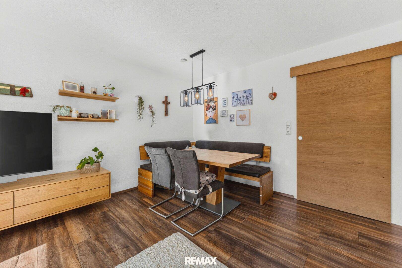 Essbereich mit Holztisch und Sitzbank, offen zum Wohnzimmer.