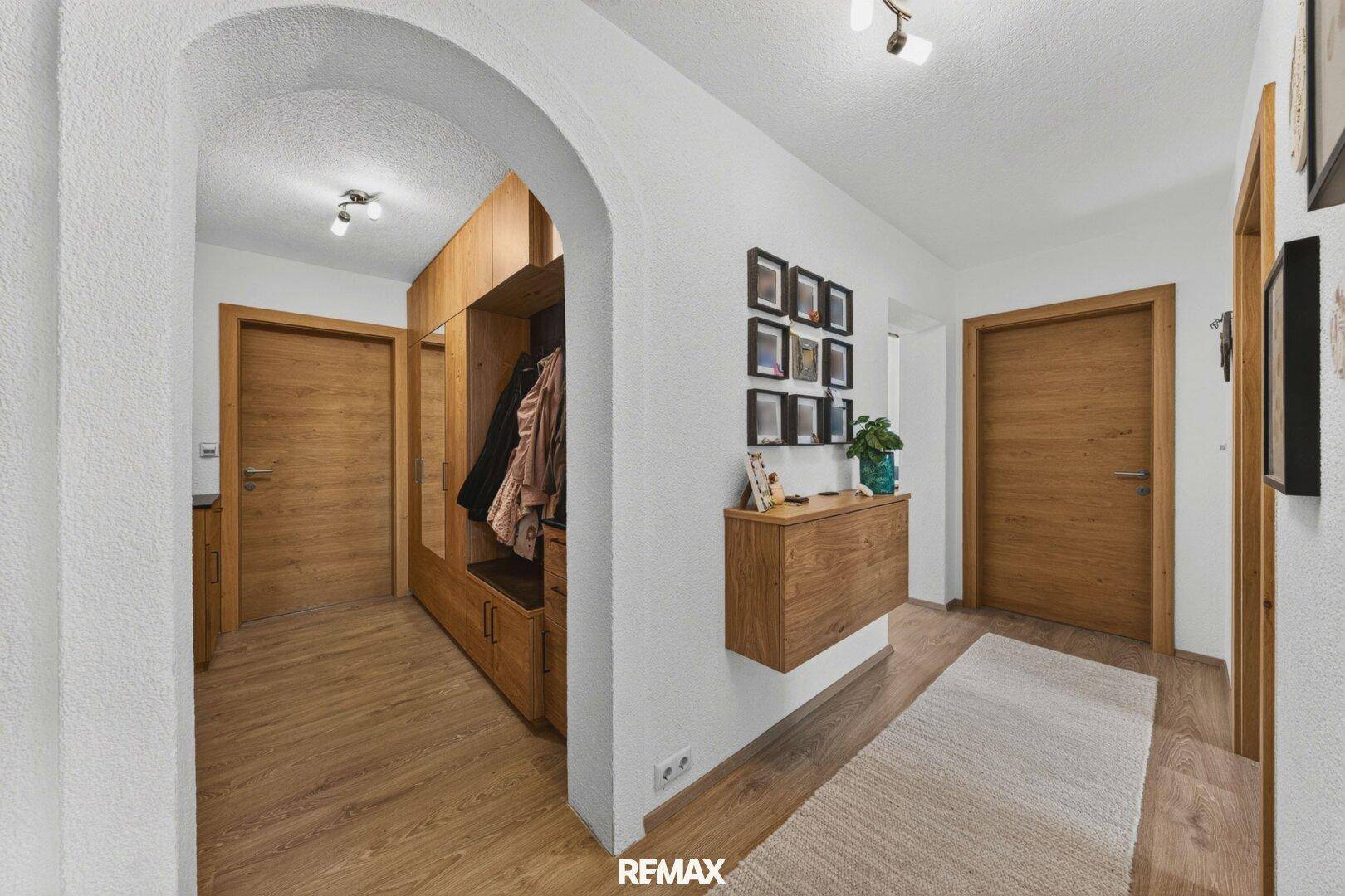 Heller Flur mit Holzboden, Garderobe und dekorativen Elementen.
