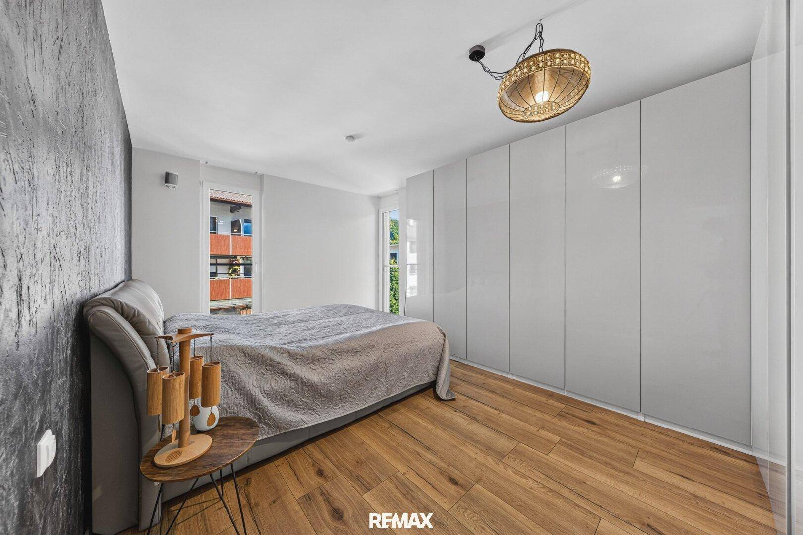 Helles Schlafzimmer mit großem Bett, Einbauschränken und Holzboden.