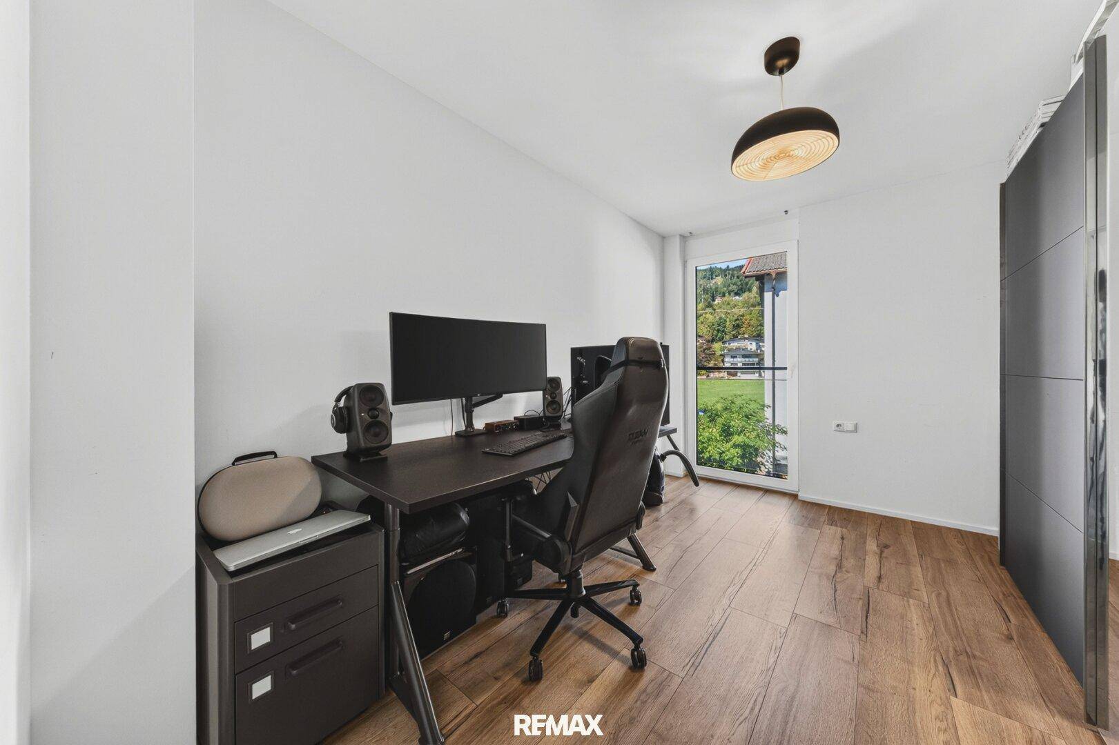 Arbeitszimmer mit Schreibtisch, Computer-Setup und Zugang zu einem Balkon.