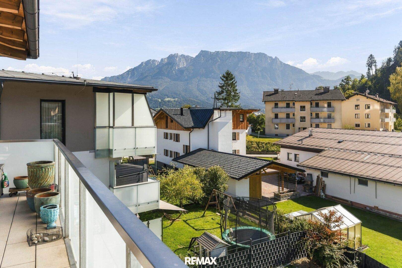 Blick vom Balkon auf die umliegende Berglandschaft und grüne Gärten.