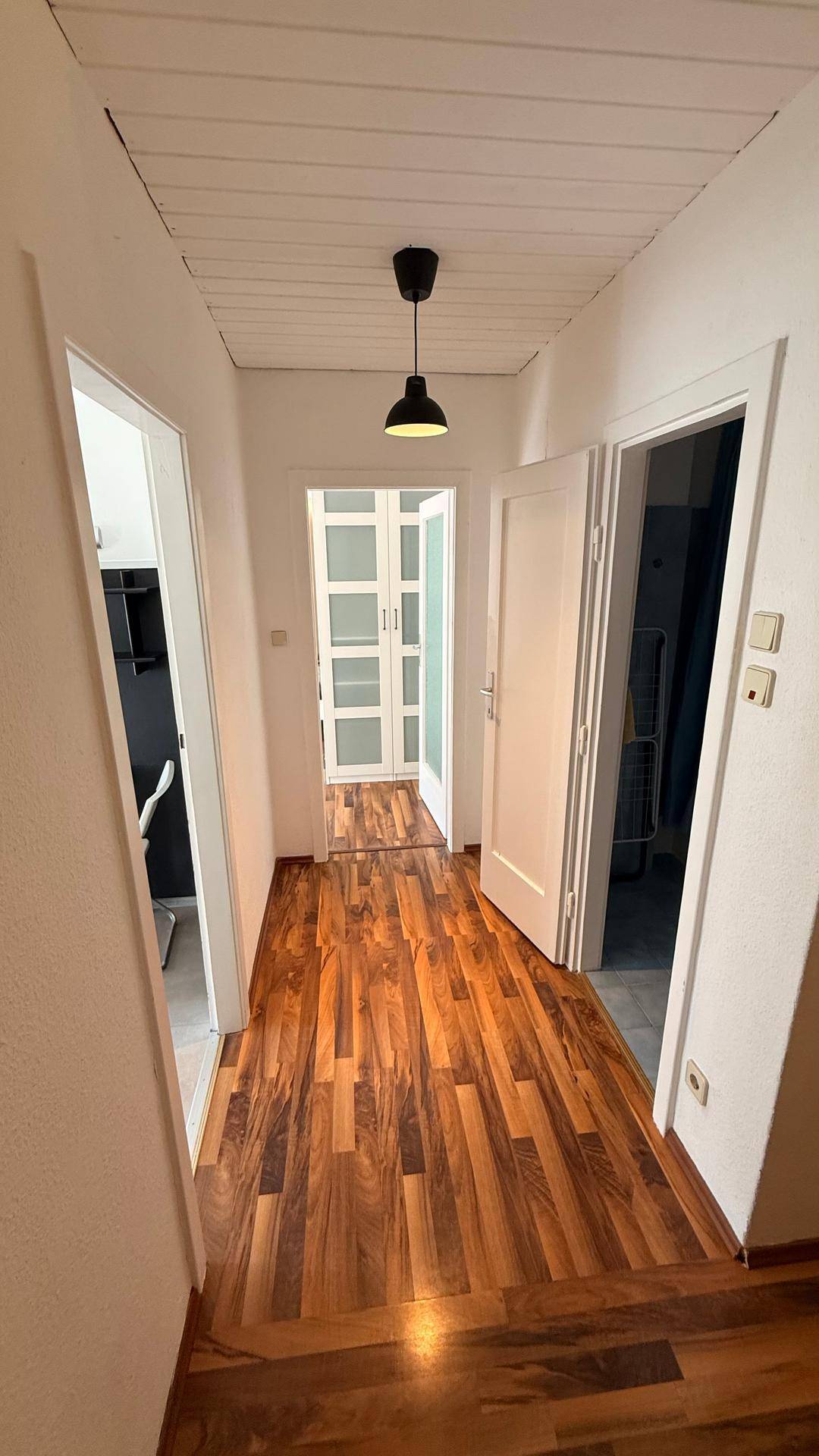 Langer Flur mit Holzboden und mehreren Türen, die zu verschiedenen Räumen führen.