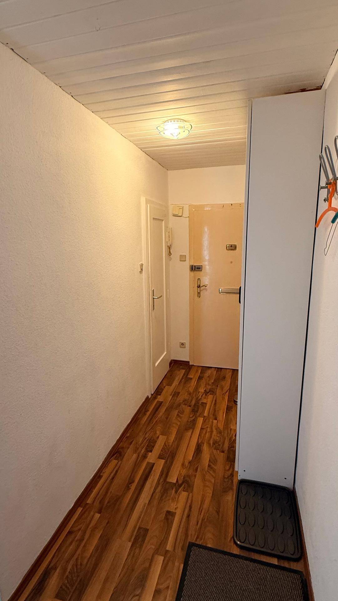 Heller Flur mit Holzboden und einer Eingangstür, die den Zugang zur Wohnung ermöglicht.