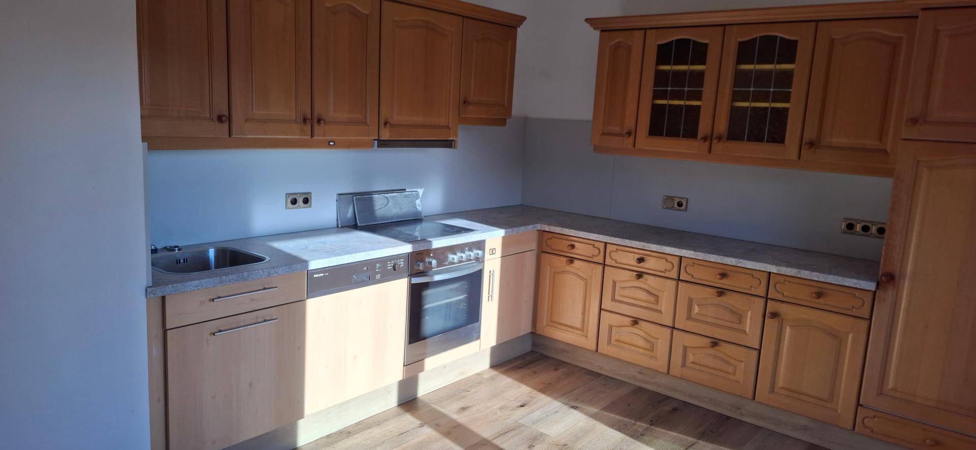 Funktionale Küche mit Holzschränken, Herd und Backofen, ideal für den täglichen Gebrauch.
