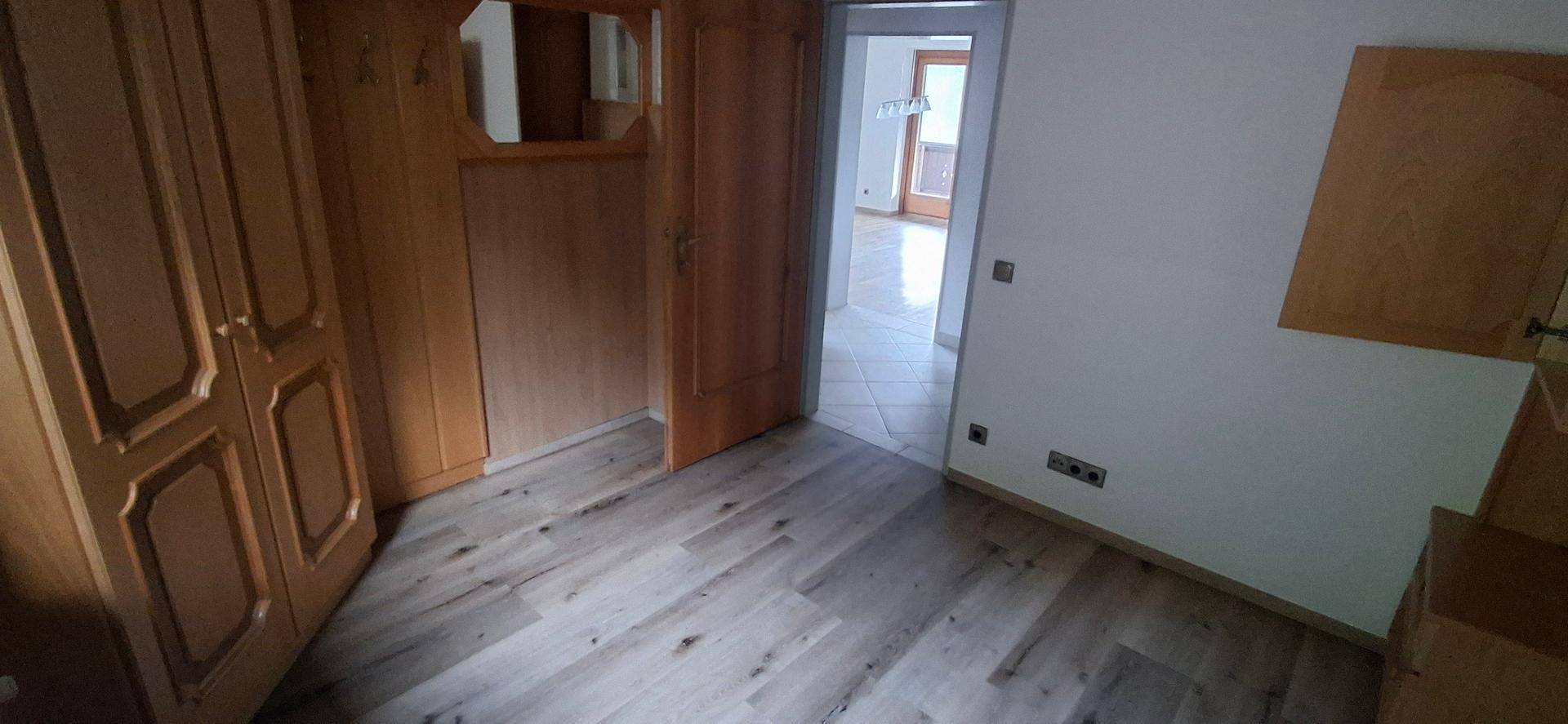 Schlafzimmer mit Holzeinbauschränken und Laminatboden, das eine gemütliche Atmosphäre schafft.