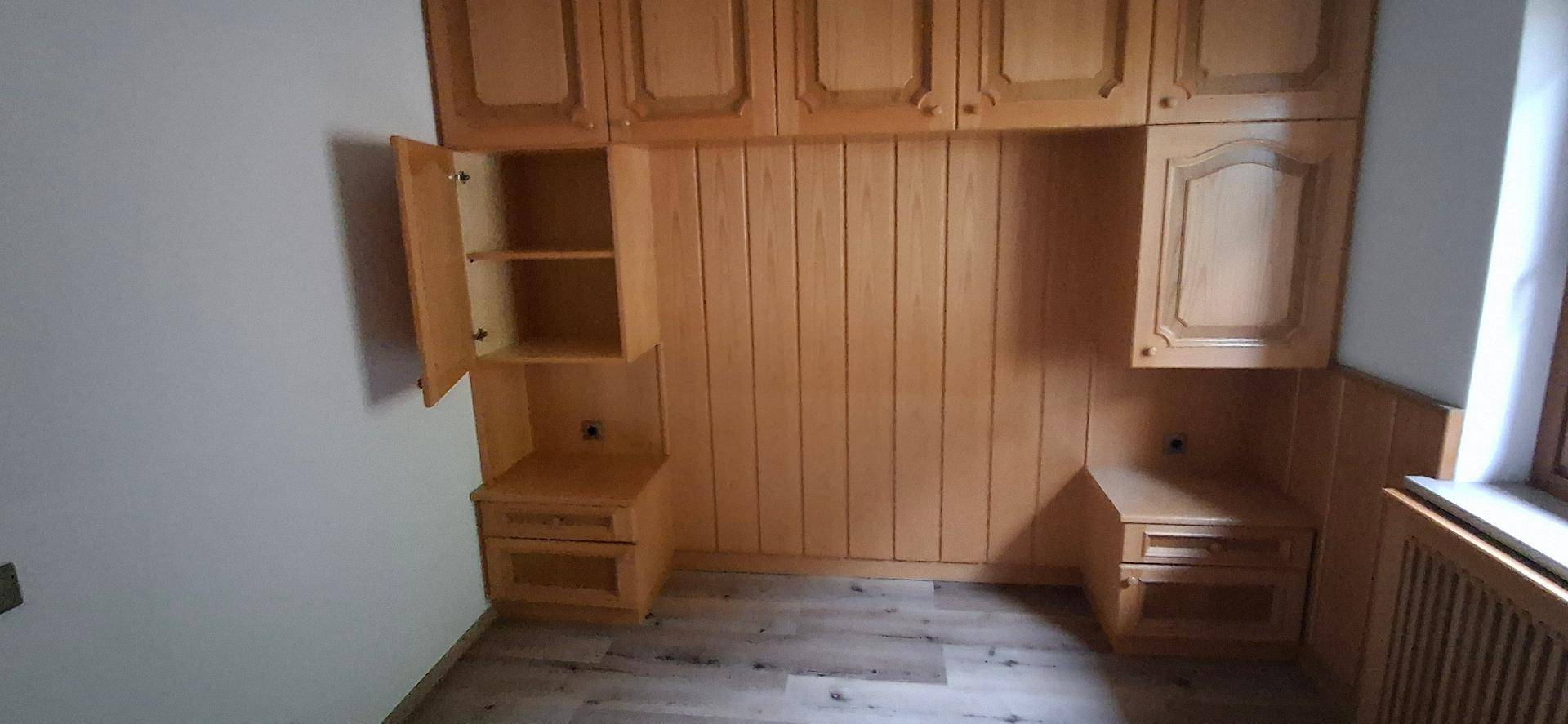 Schlafzimmer mit Einbauschränken und Nachttischen aus Holz, die eine funktionale Einrichtung bieten.