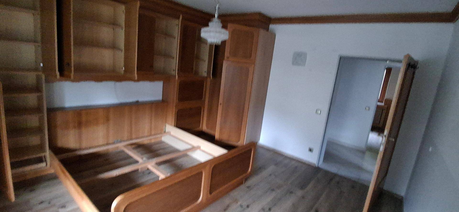 Schlafzimmer mit Holzbettrahmen und offenen Regalen, die viel Stauraum bieten.
