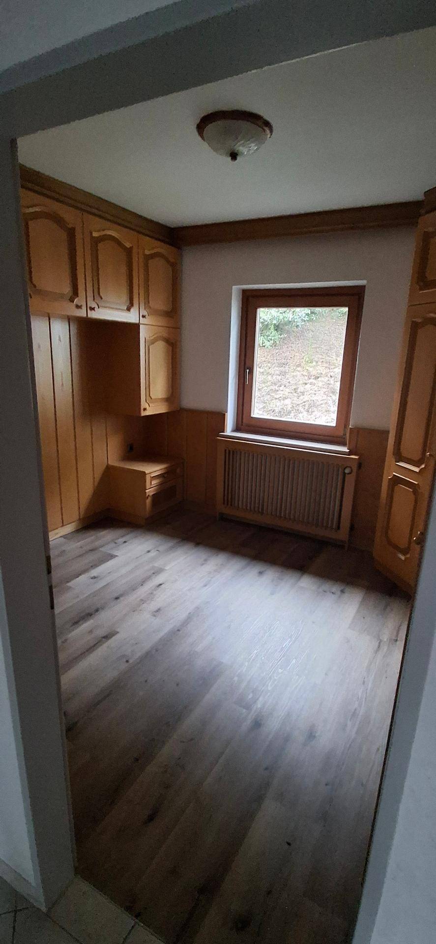 Schlafzimmer mit Fenster und Einbauschränken aus Holz, die viel Stauraum bieten.