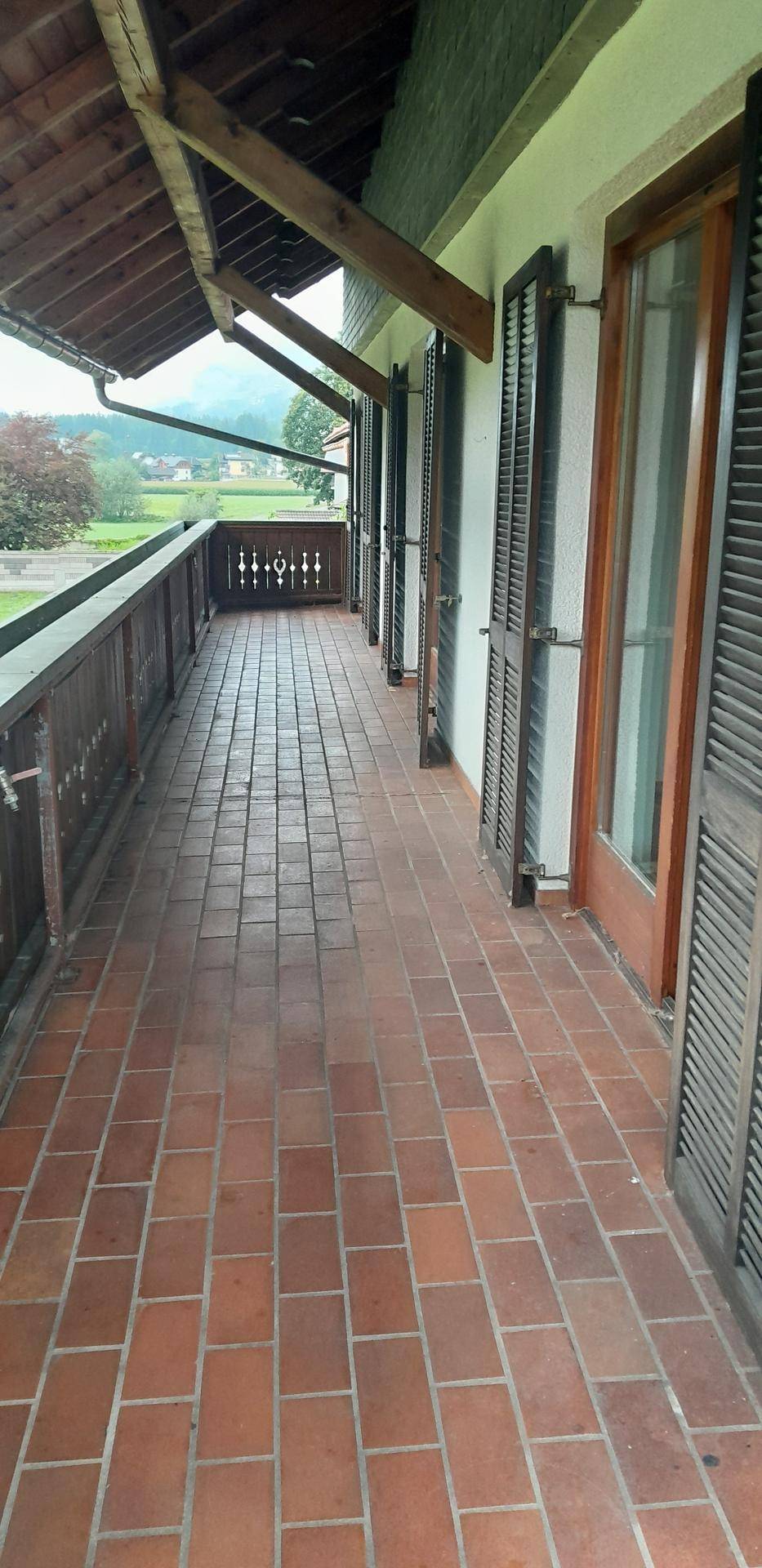 Geräumiger Balkon mit Terrakottafliesen und Holzgeländer, der einen weiten Blick bietet.
