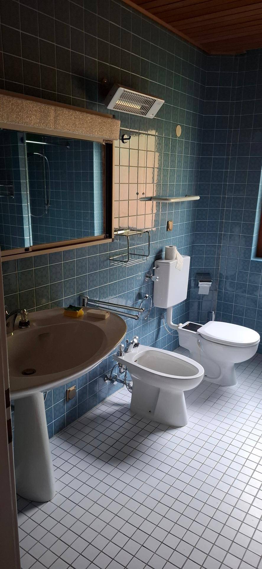 Badezimmer mit blauen Fliesen, Waschbecken, WC und Bidet, das eine komplette Ausstattung bietet.