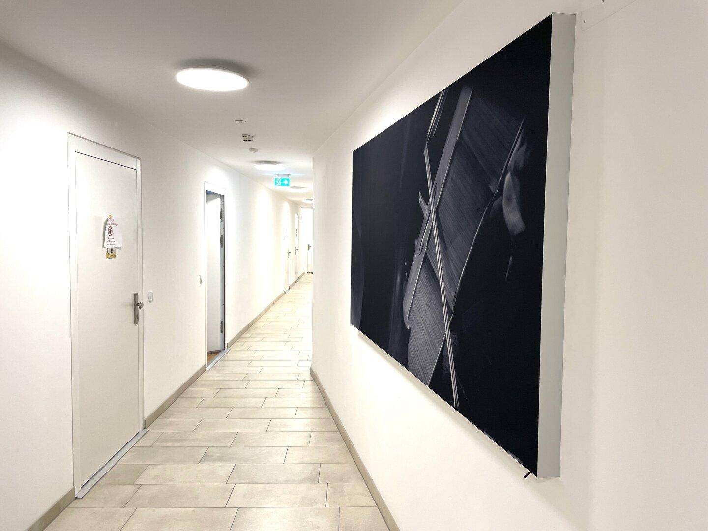 Langer Flur mit Fliesenboden und moderner Kunst an der Wand.