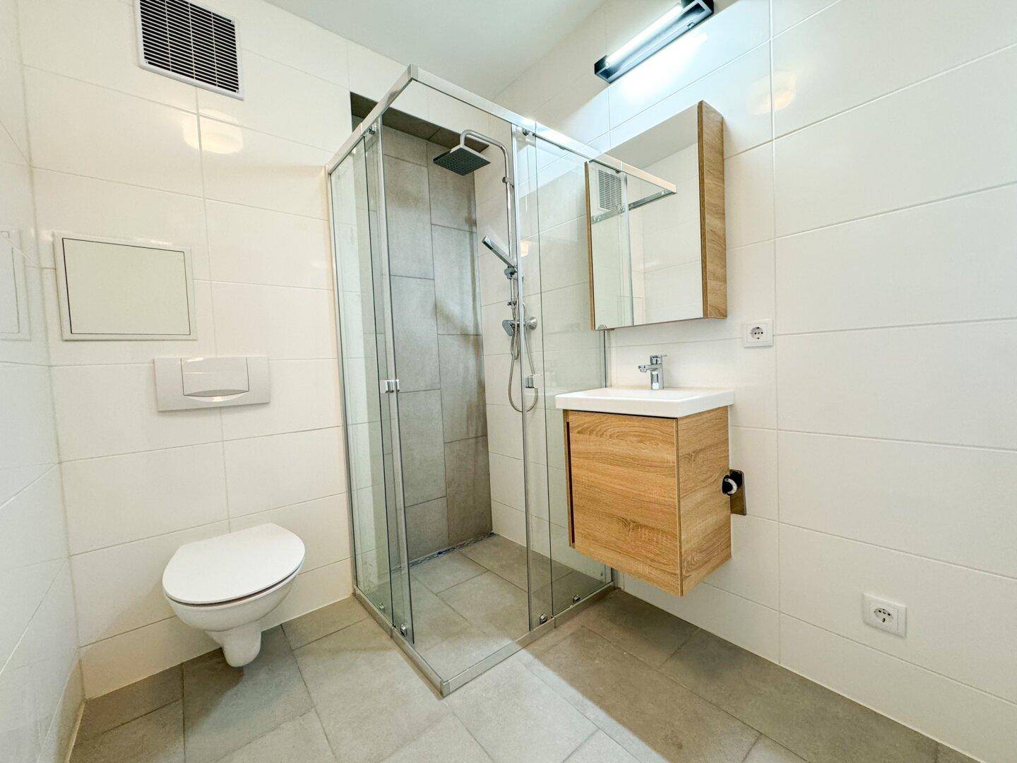 Modernes Badezimmer mit Duschkabine, Waschbecken und wandhängendem WC.
