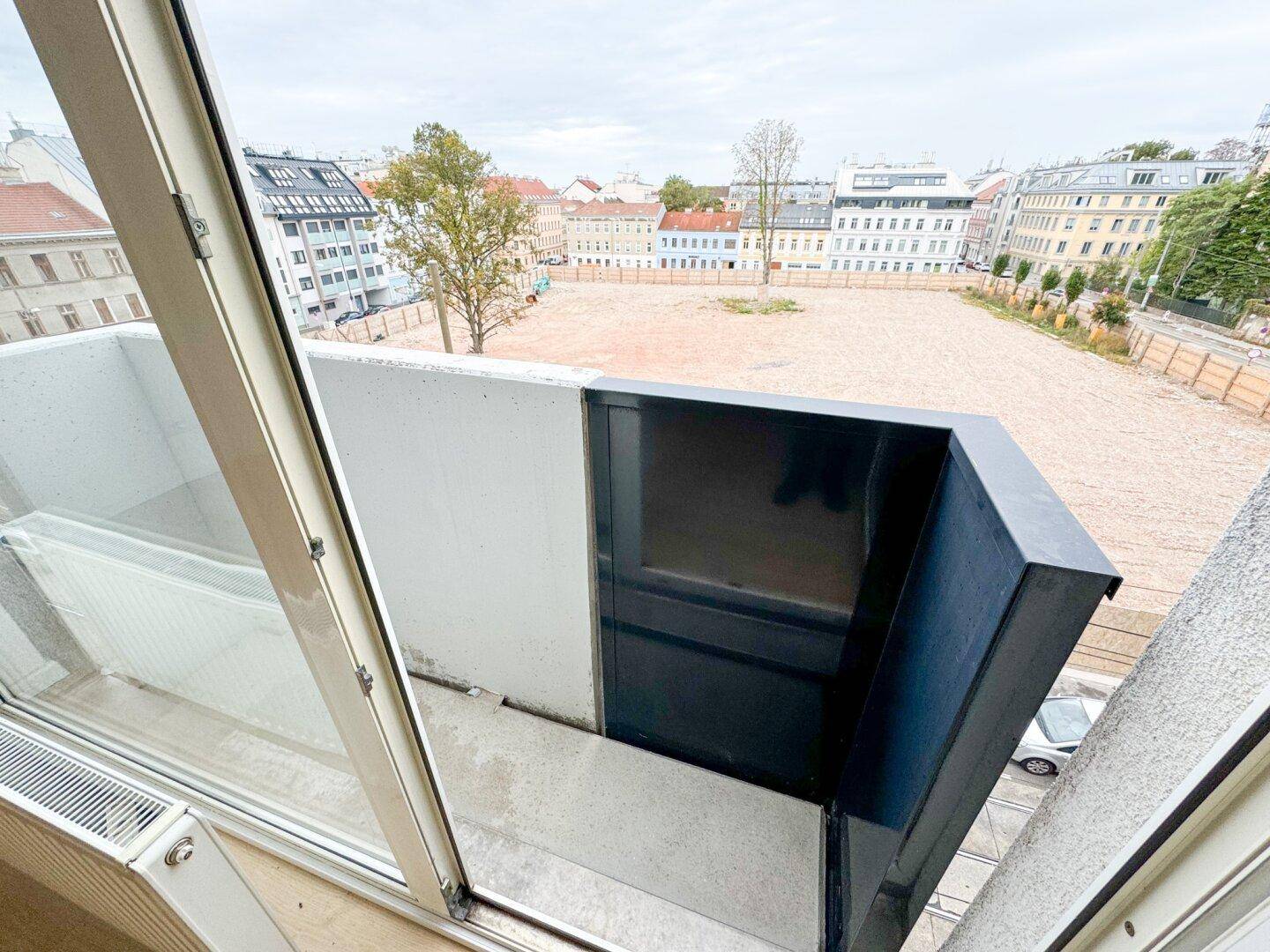 Kleiner Balkon mit Blick auf eine Baustelle und städtische Umgebung.