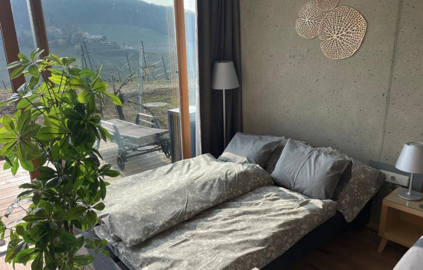 Helles Schlafzimmer mit großem Fenster und Blick auf die Weinberge, ausgestattet mit einem bequemen Bett.