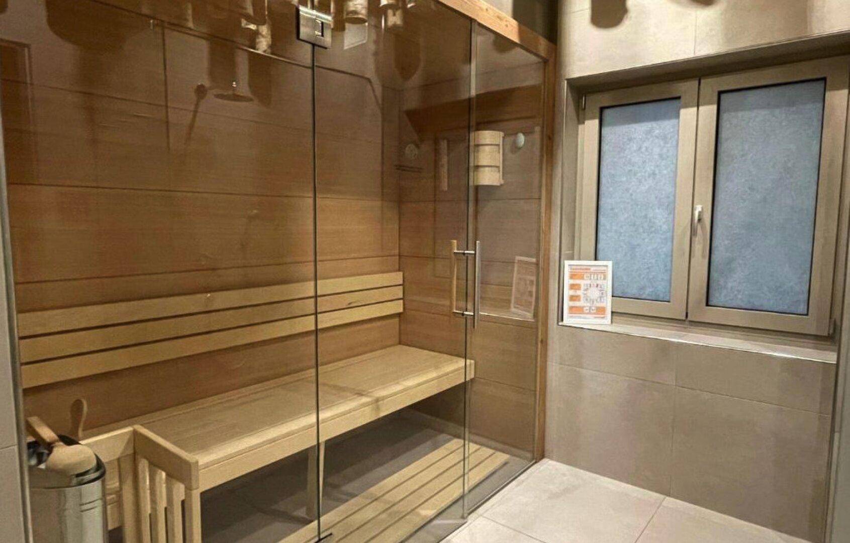 Moderne Sauna mit Holzbänken und Glasfront, ideal zur Entspannung nach einem aktiven Tag.
