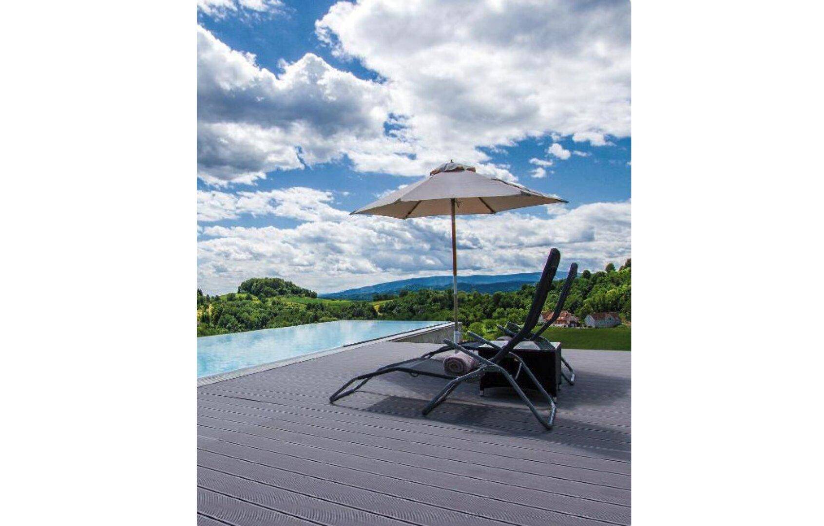 Entspannungsbereich am Pool mit Liegestühlen und Sonnenschirm, umgeben von einer malerischen Landschaft.