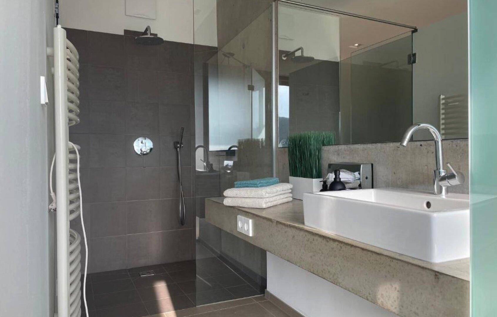 Modernes Badezimmer mit großer begehbarer Dusche, Einzelwaschbecken und beheiztem Handtuchhalter.
