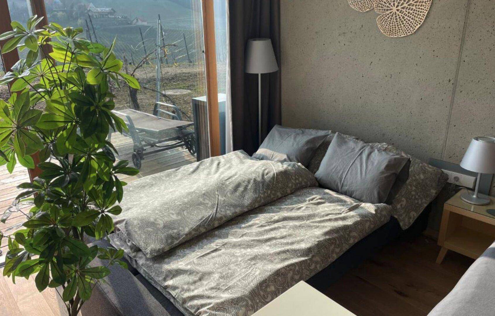 Helles Schlafzimmer mit großem Fenster und Blick auf die Weinberge, ausgestattet mit einem bequemen Bett.