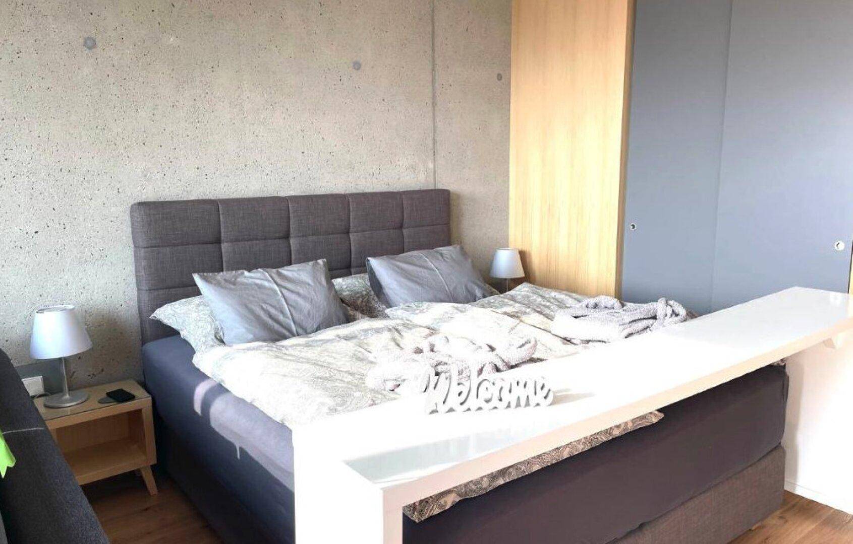 Helles Schlafzimmer mit Doppelbett, Nachttischen und integrierten Schränken.