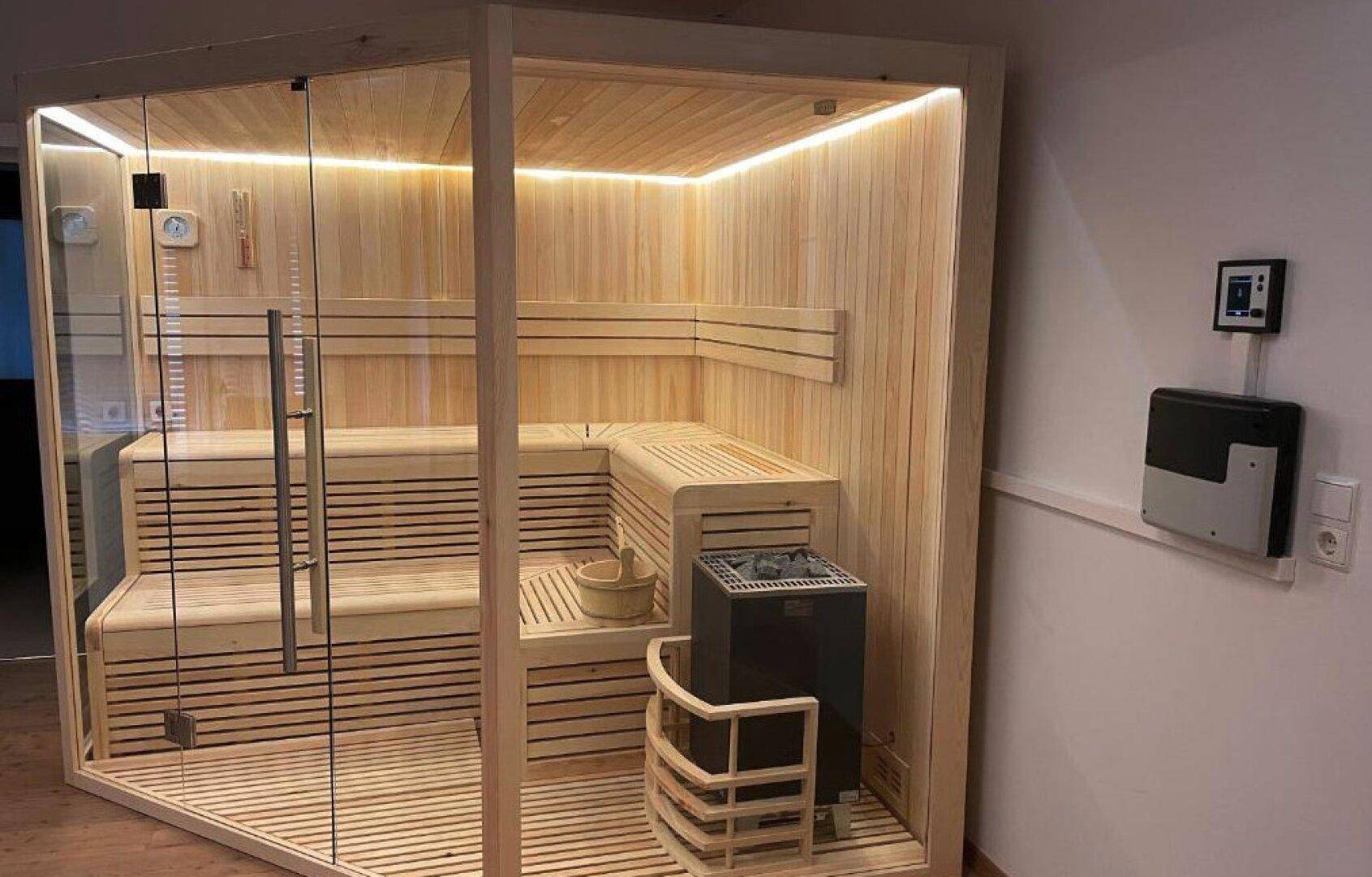 Moderne Holzsauna mit Glasfront und indirekter Beleuchtung für entspannende Momente im Wellnessbereich.