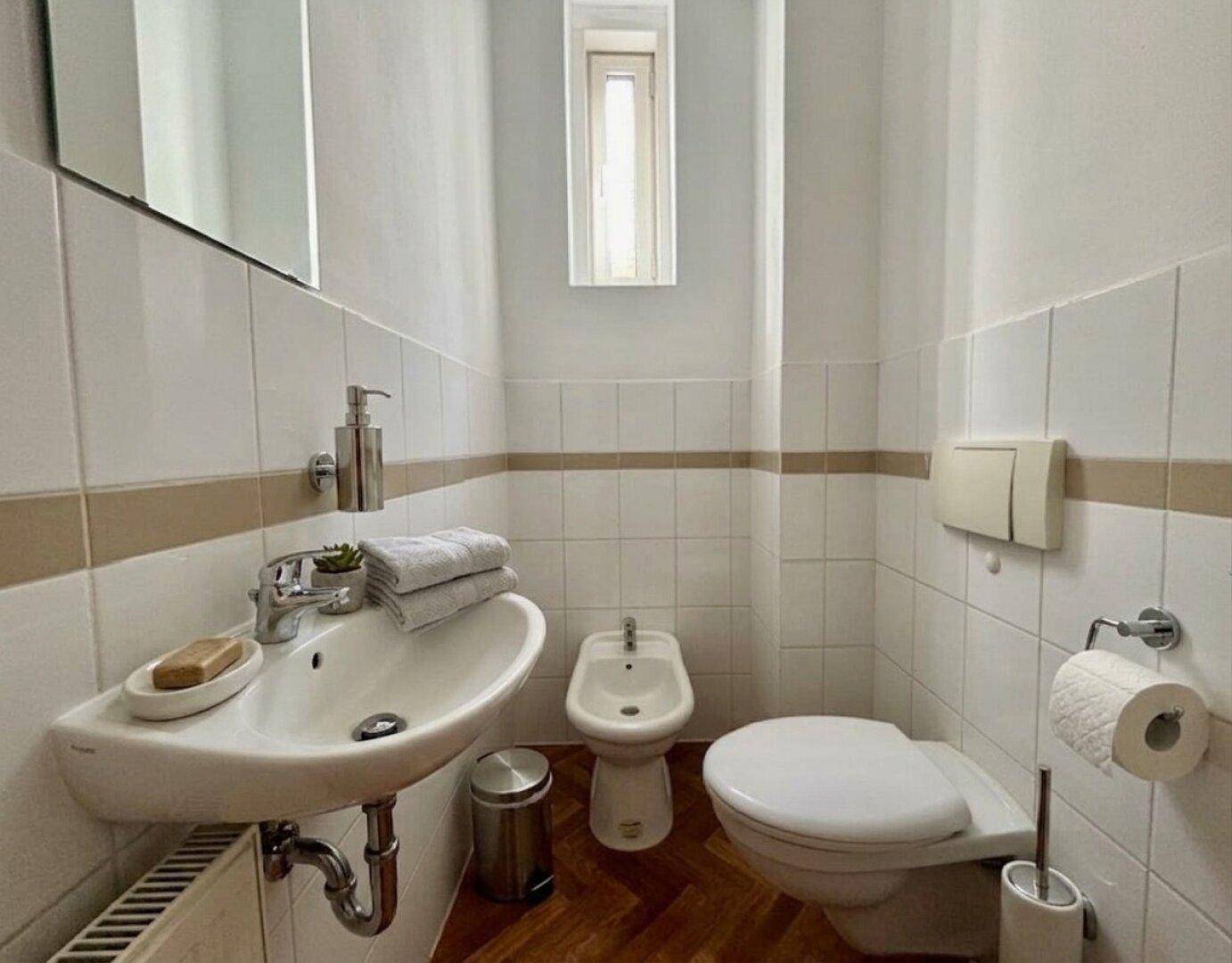 Separate Toilette mit Waschbecken, Bidet und Fenster.