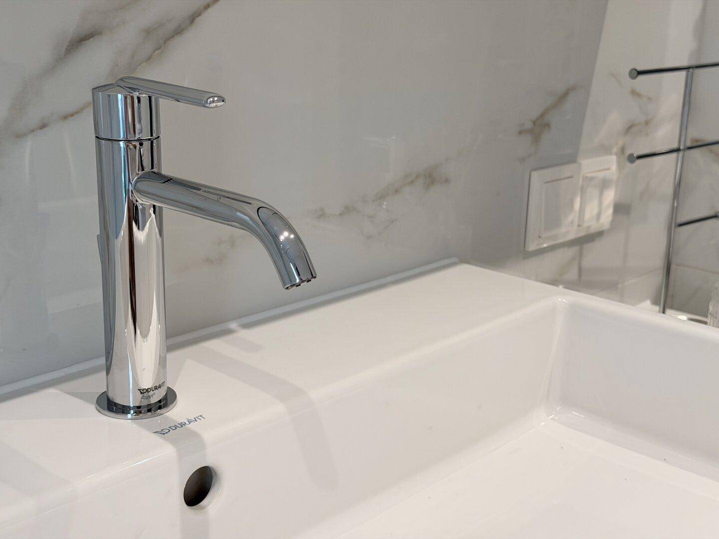 Detailansicht des modernen Wasserhahns und des Waschbeckens im eleganten Badezimmer.