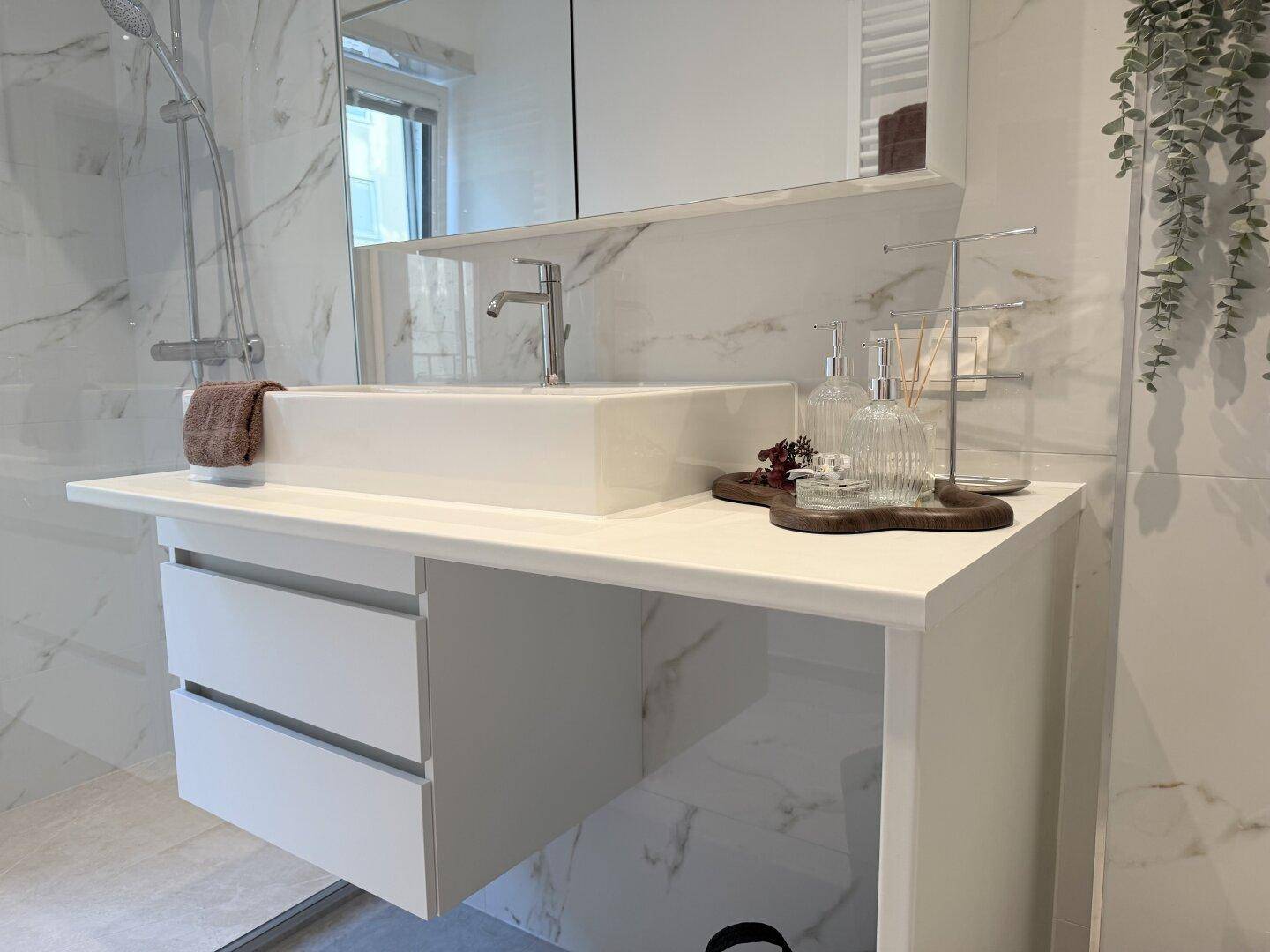 Moderner Waschtisch mit Schubladen und Aufsatzwaschbecken in einem hellen Badezimmer.