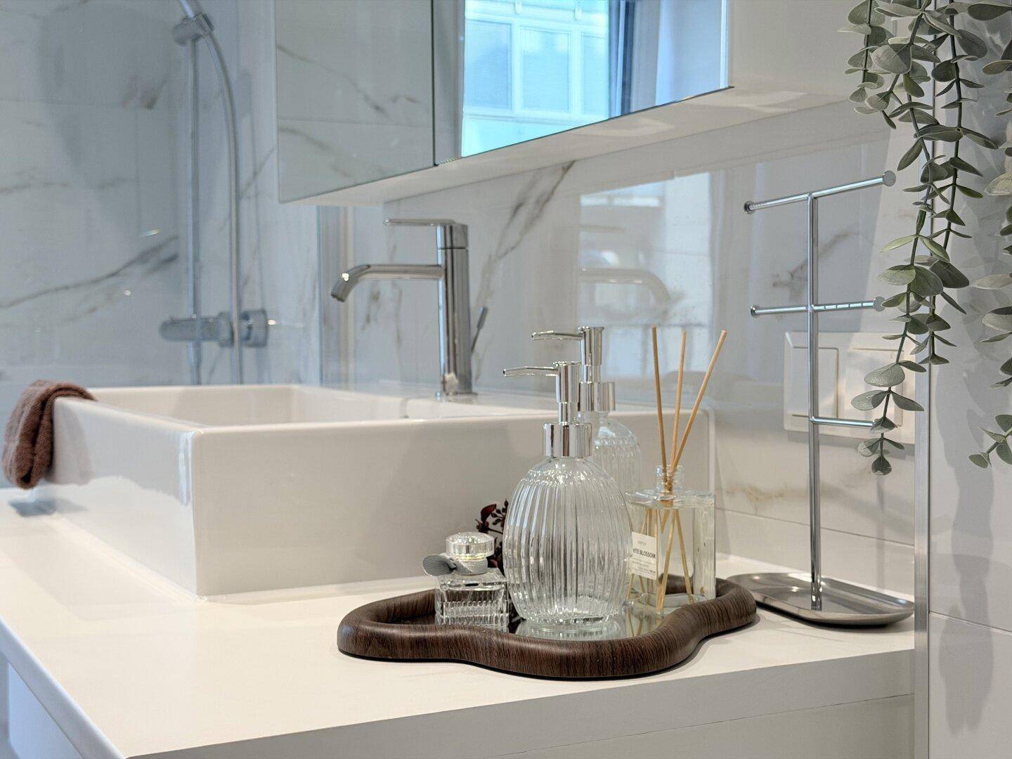 Nahaufnahme des Waschtischs mit modernem Waschbecken und stilvollen Accessoires im Badezimmer.