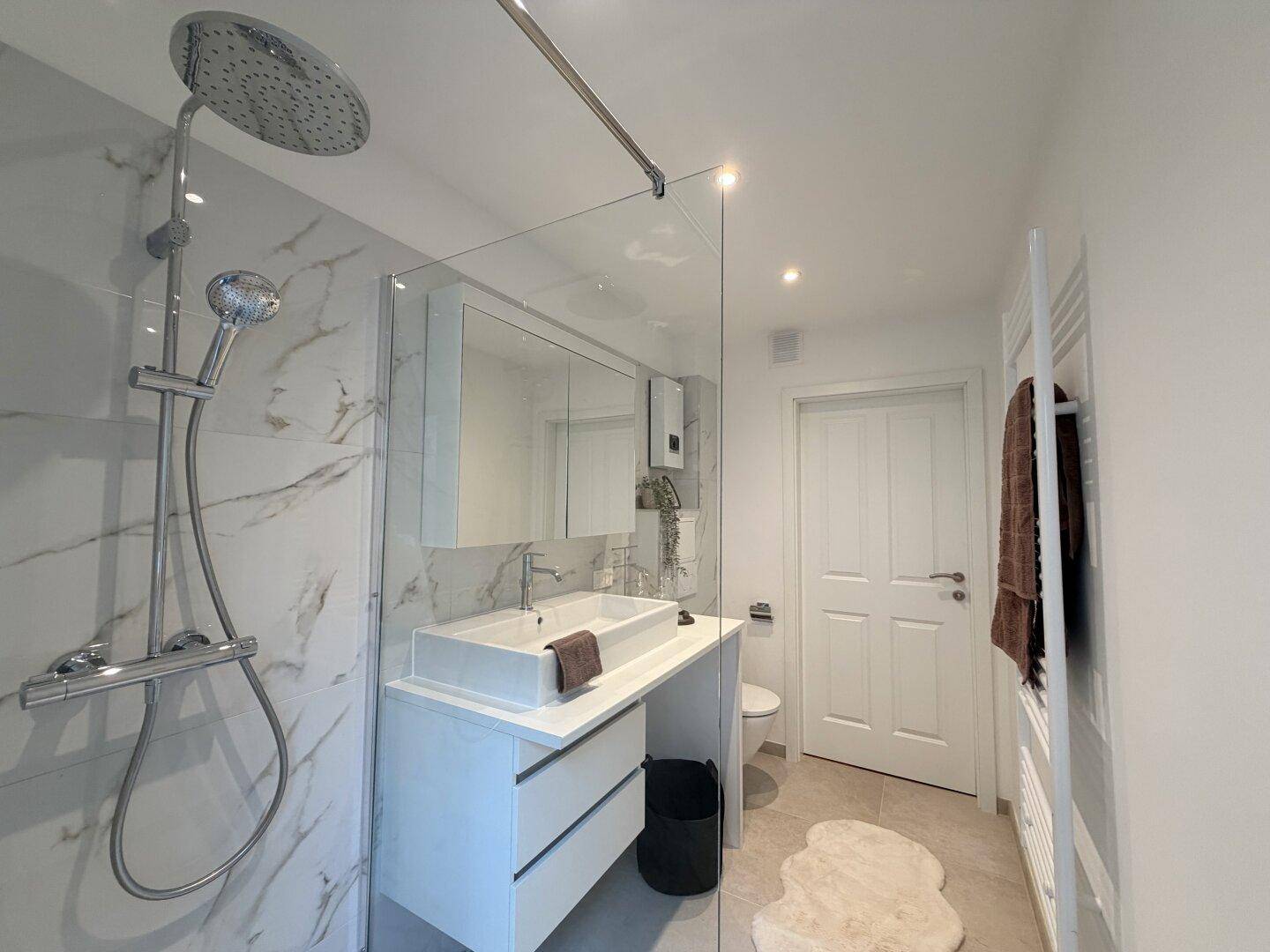 Geräumiges Badezimmer mit ebenerdiger Dusche, Waschtisch und Toilette, hell und modern.
