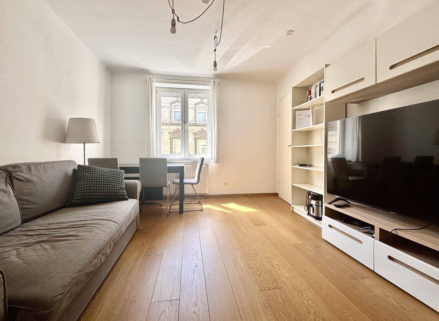 Gemütlicher Wohn-Essbereich mit Sofa, Esstisch und Blick auf die Straße.