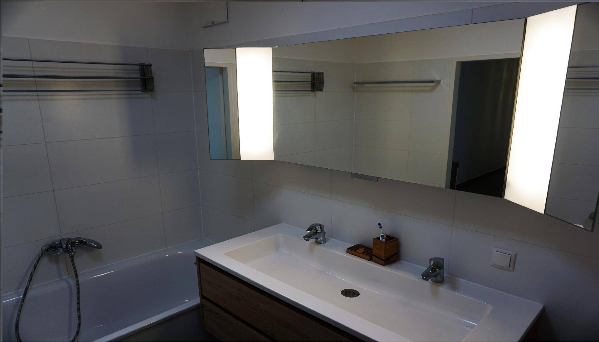 Modernes Badezimmer mit Badewanne, Einzelwaschbecken und Spiegelschrank.