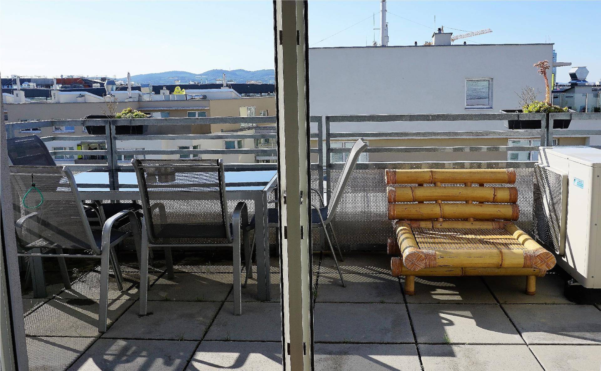 Sonnige Dachterrasse mit Sitzgelegenheiten und weitem Blick über die Stadt.